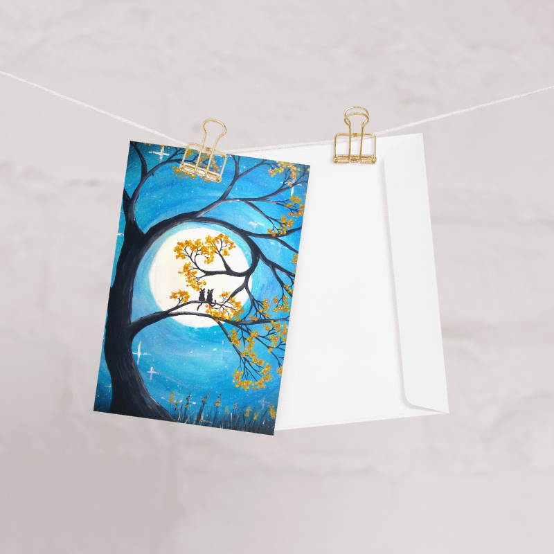 A greeting card with a full moon and two cats design.