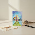 Greeting card with a colorful design of a cross on an island with mountains and sky.