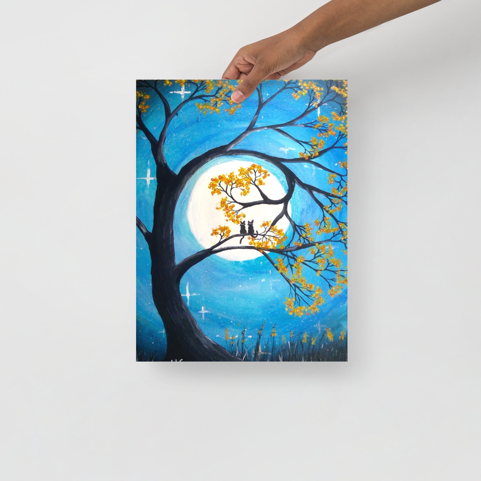 Painting of a tree with yellow leaves and a full moon, held by a hand on a white background.