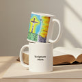 Two white ceramic mugs stacked on a white background. The top mug is tilted to show a colorful hand-drawn illustration of a crucifix scene with blue, yellow, green, and orange tones.