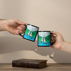 Two white ceramic mugs stacked vertically, featuring a colourful hand-drawn style illustration of a sailboat on blue water with green hills and white clouds.