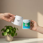 Two hands holding white ceramic mugs against a plain white background. The mug on the left is plain white with the text 'Scripture Here' printed in black. The mug on the right has a colourful illustration of a sailboat and a girl. 
