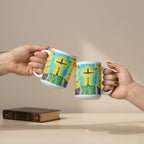 Two white ceramic mugs with a colorful illustration of a cross on a hill under a blue and yellow sky, held by two hands against a white background.